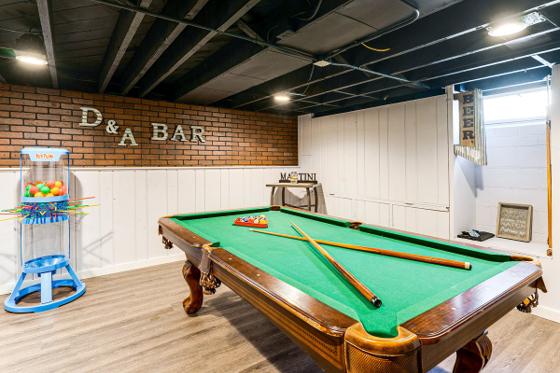 Basement game area with a full-size pool table against an exposed brick wall