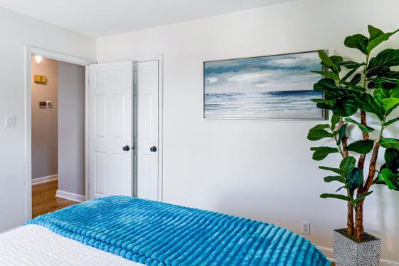Guest bedroom with a teal bedspread, double closet and framed ocean print