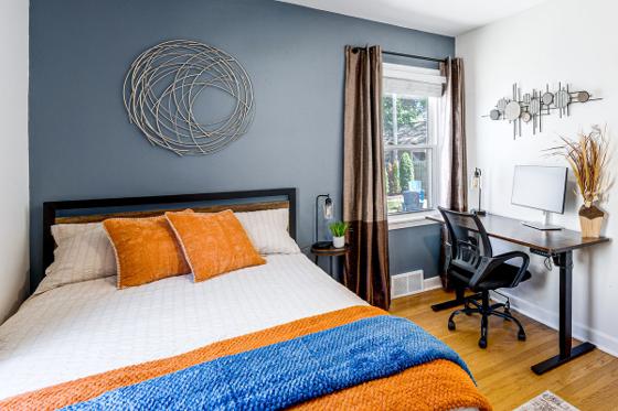 Bedroom with a navy accent wall and a desk set up as a work-from-home space