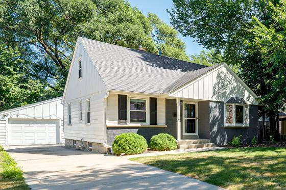 Front exterior of the house with a mature shade tree, driveway and detached garage