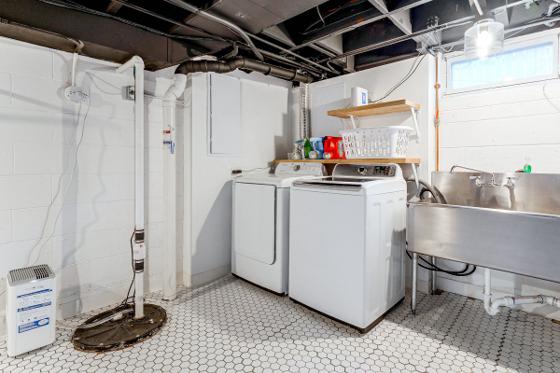 Basement laundry room with a full-size washer and dryer and a utility sink